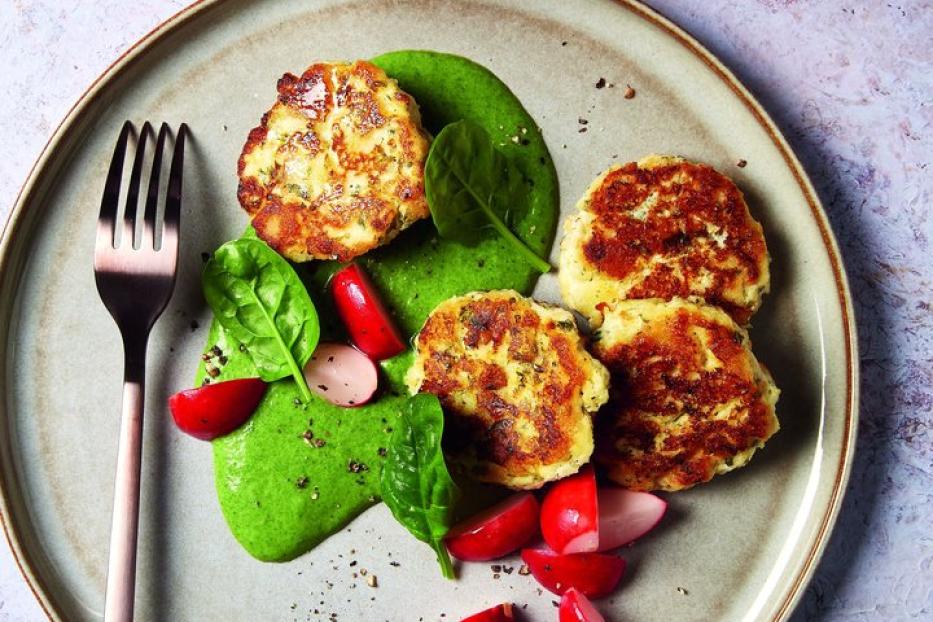 Ein Teller mit Kartoffelpuffern, Radieschen, Spinat und einem grünen Dip, dazu ein Getränk mit Limette.