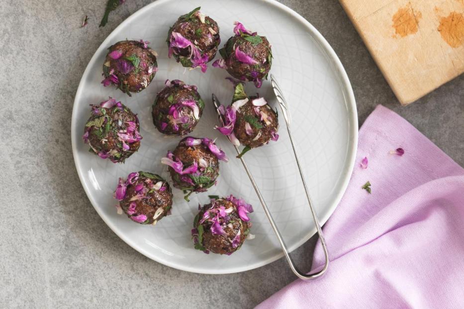 Fleischbällchen werden mit einer Mischung aus Kräutern und Rotkohl garniert.