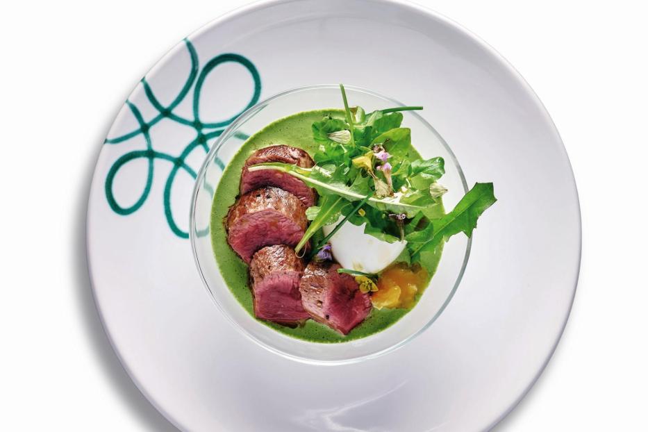 Ein Gericht mit Maibock, Salat und grüner Soße wird auf einem Teller serviert.