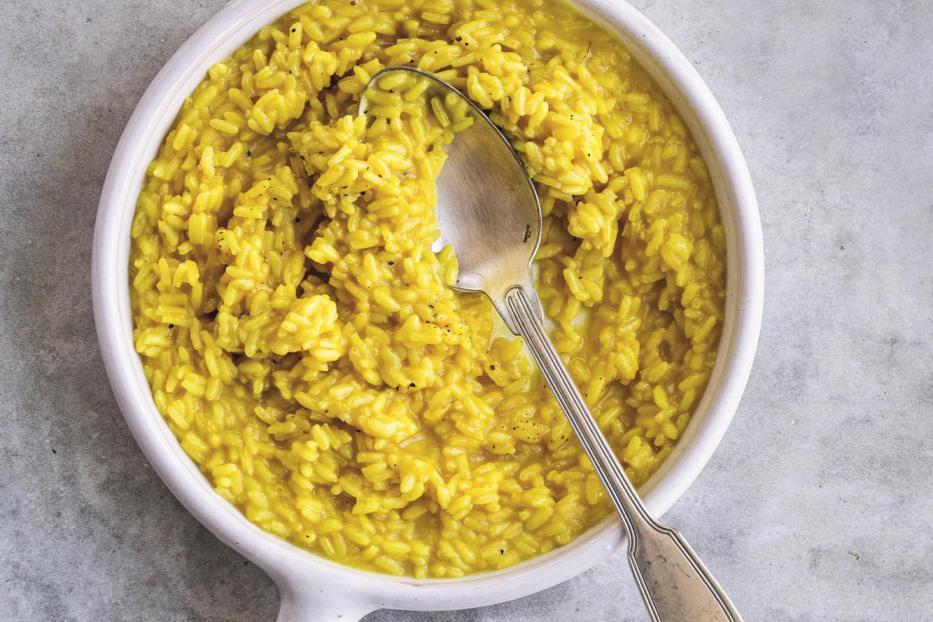 Ein Teller Risotto mit Safran und einem Löffel darauf.