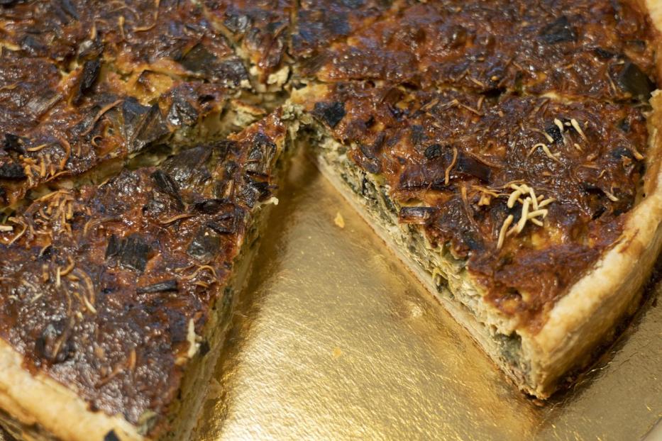 Eine Quiche mit Gemüse und Käse auf einem goldenen Teller.