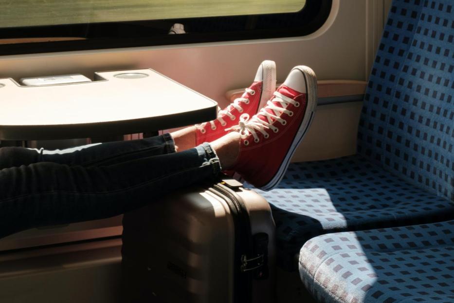 Füße mit Schuhen und ein Koffer in der Deutschen Bahn