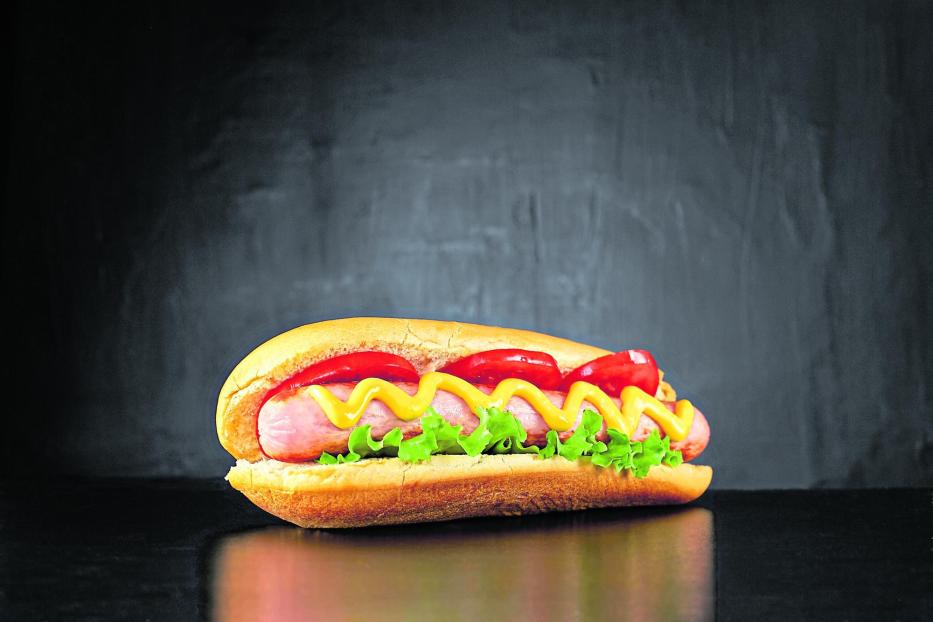 Big hotdog with sausage tomatoes, mustard and salad isolated