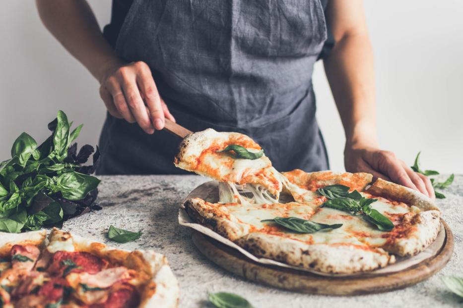 Mann serviert Pizza, Käse zieht Fäden