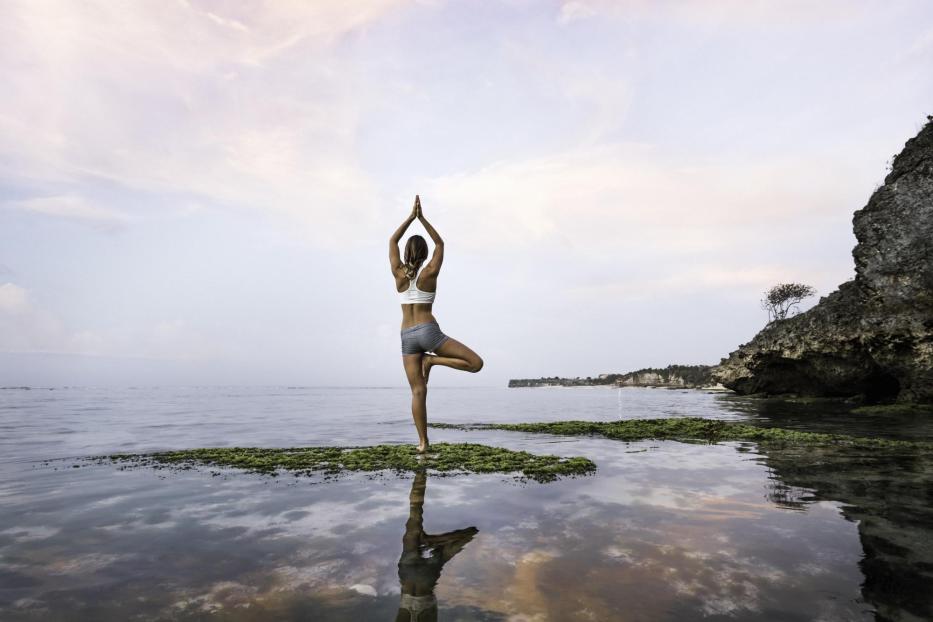 Frau praktiziert Yoga am See