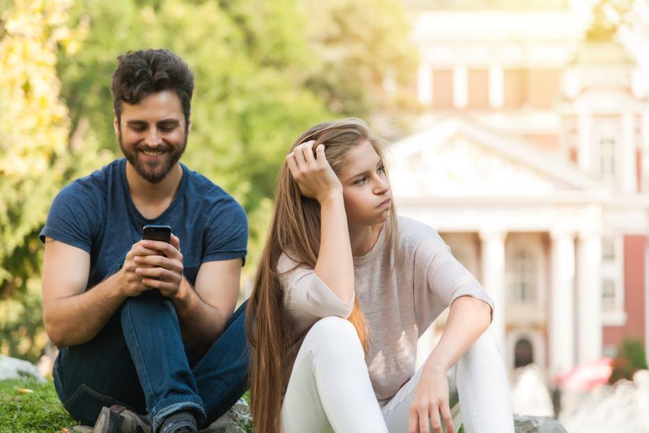 Mann und Frau nebeneinander, er am Handy