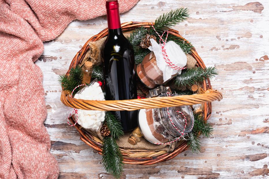 Rotwein und Konfektgläser in einem weihnachtlichen Präsentkorb