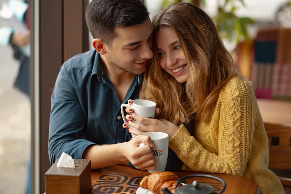 Paar in einem Café beim Date, kuschelt