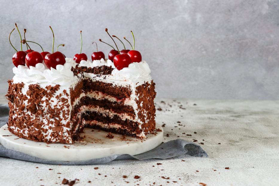 Angeschnittene Torte mit Schlagobers und Kirschen