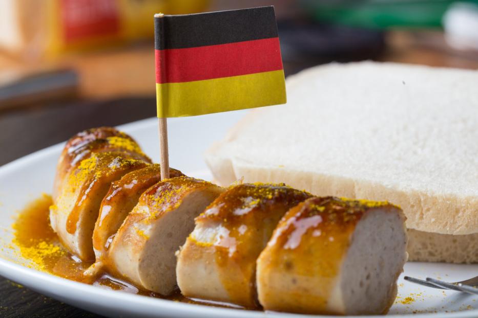 Auf einer Currywurst steckt eine Papierflagge mit den deutschen Farben Schwarz, Rot, Gold