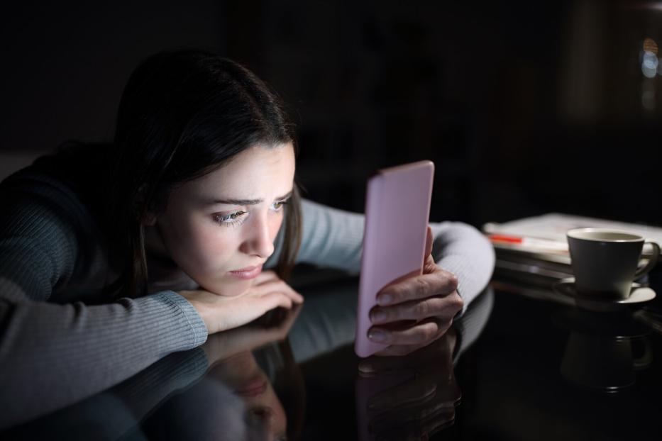 Frau schaut traurig auf ihr Smartphone