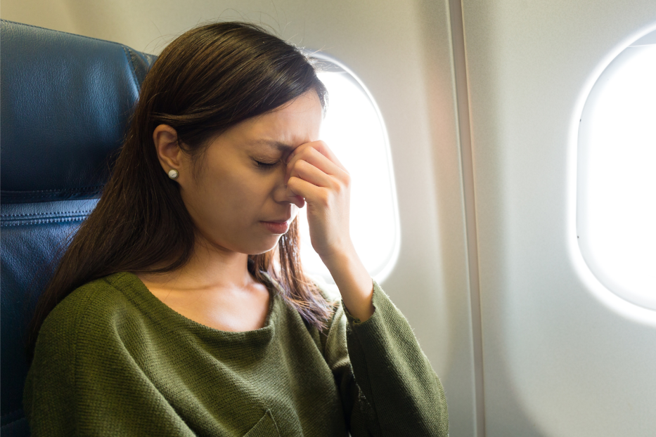 Frau sitzt ängstlich im Flugzeug, was man bei Flugangst machen sollte 