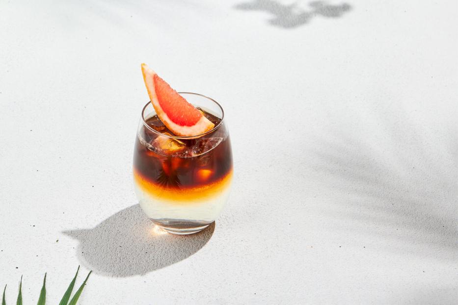 Espresso Tonic mit Orangenscheibe auf weißem Hintergrund