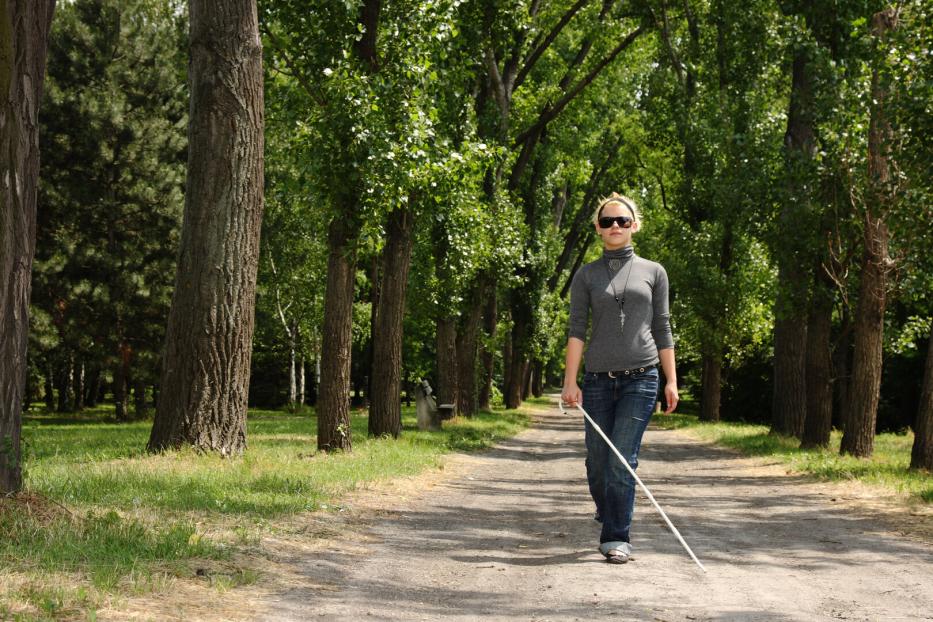 Frau mit Blindenstock im Park