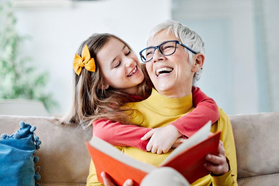 Eine Großmutter liest mit ihrem Kind ein Buch.