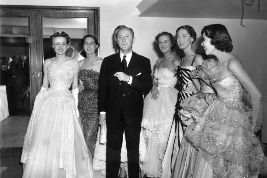 Christian Dior mit sechs Models in seinen eleganten Abendroben im Jahr 1950