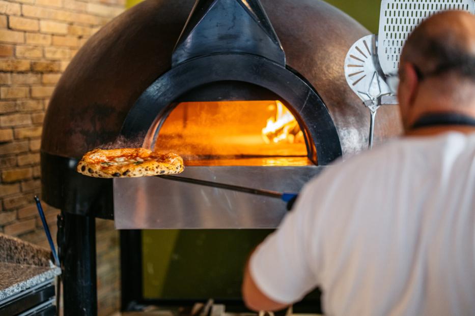 Mann schiebt Pizza in den Ofen