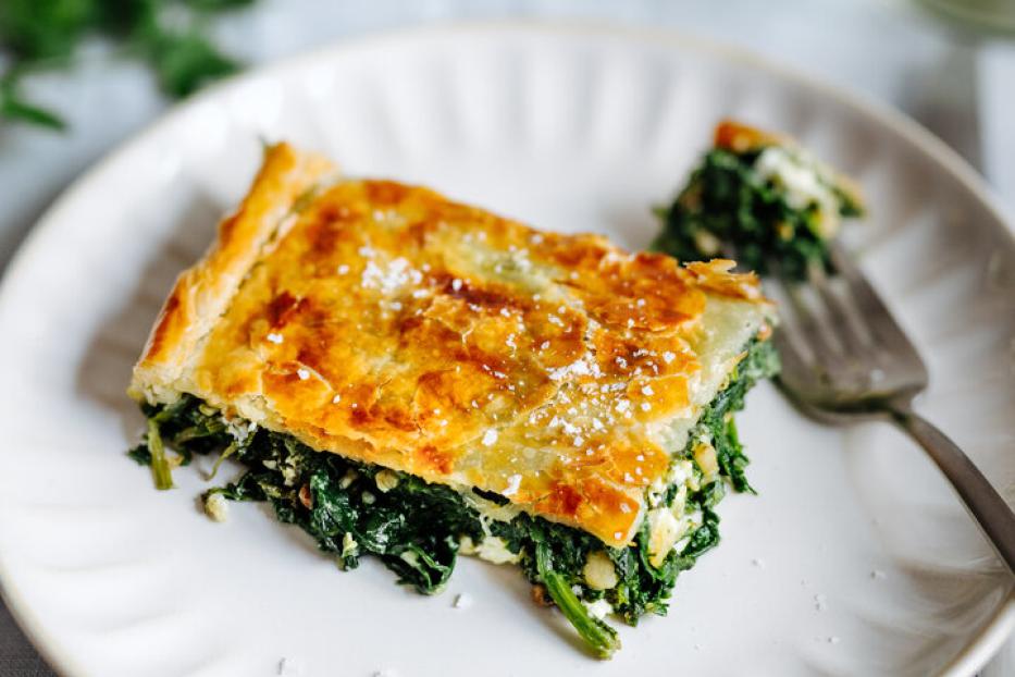 Ein Stück Spinatpastete auf einem weißen Teller.