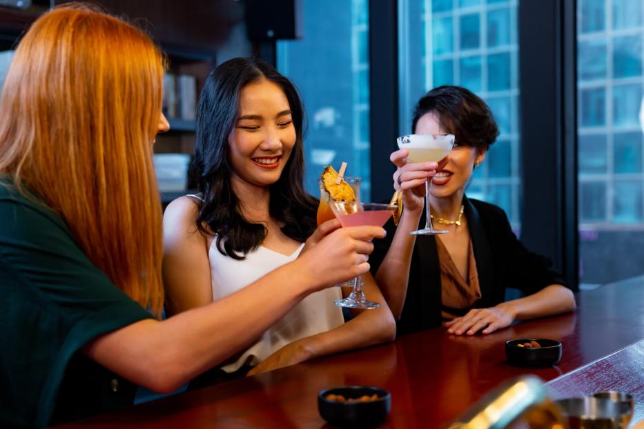 Eine Gruppe von jungen Frauen stoßt mit Cocktails an der Hotelbar an.