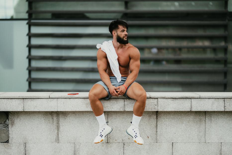 Muscular man relaxing after exercising in the city park