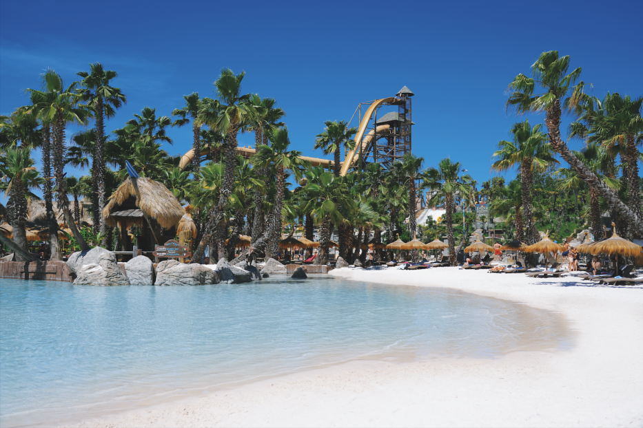 Auf dem Bild ist ein Wasserpark in Jesolo zu sehen. Klares, türkises Wasser und Rutschen im Hintergrund.