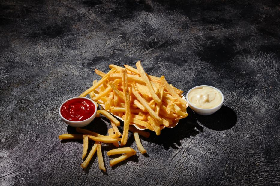 French fries in fryer basket on dark background