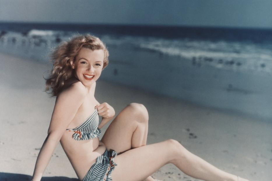 Stilikone Marilyn Monroe posiert im Bikini am Strand.