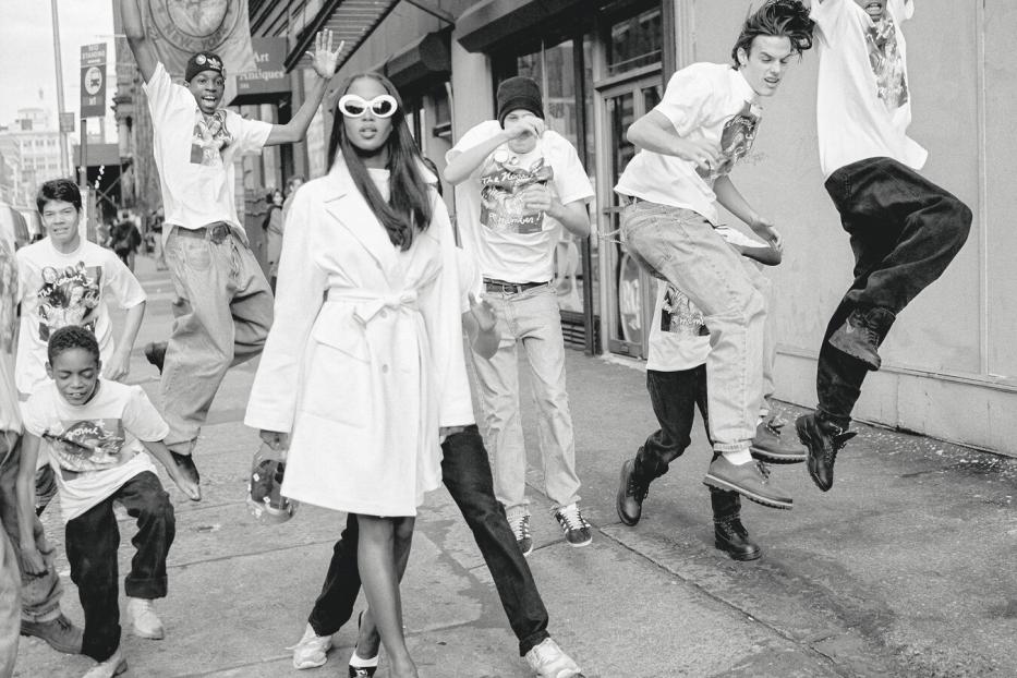 Naomi Campbell auf der Straße, rundherum springen junge Männer und Buben mit Baggy-Pants.