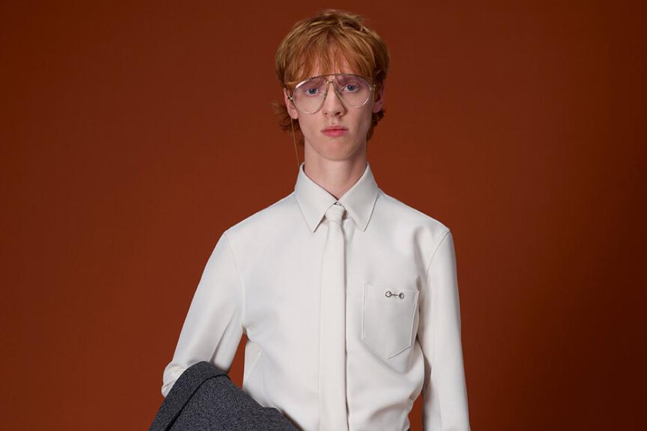 Ein Mann mit Brille hält eine grüne Gucci Reisetasche.