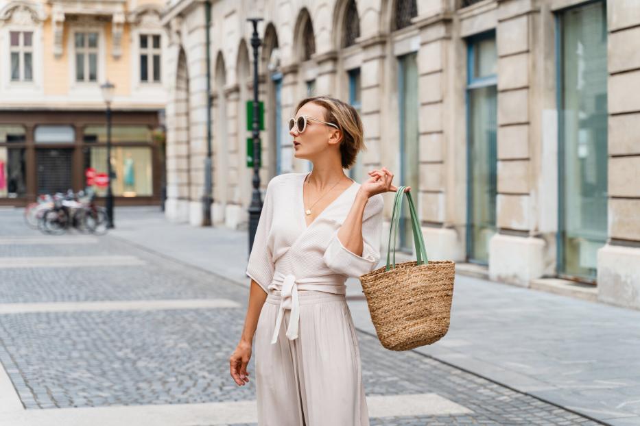 Eine stilvoll gekleidete, gut gelaunte Frau erkundet eine europäische Altstadt.