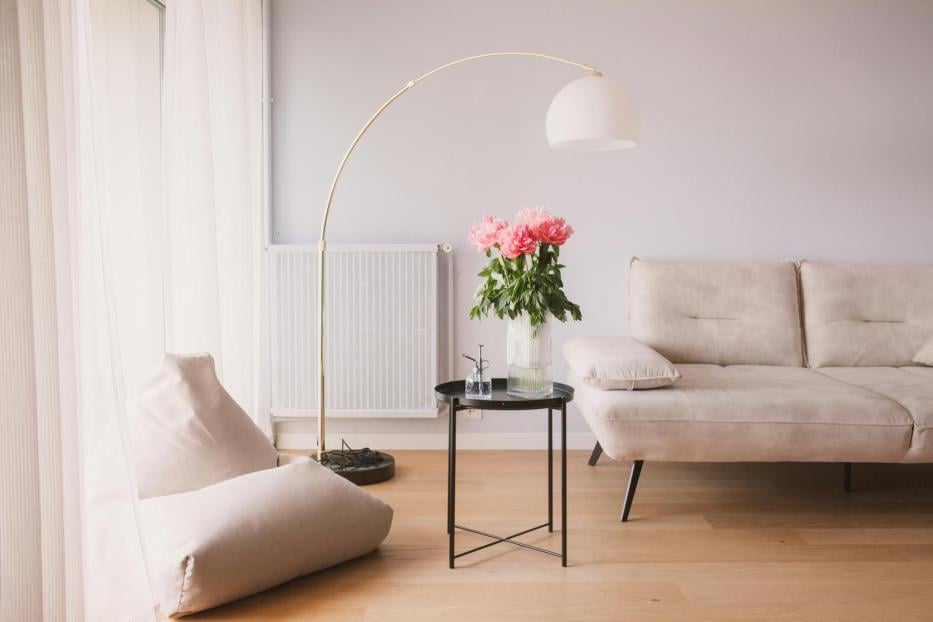 Ein Wohnzimmer mit einem Sofa, einem Tisch und einer Vase mit Blumen.