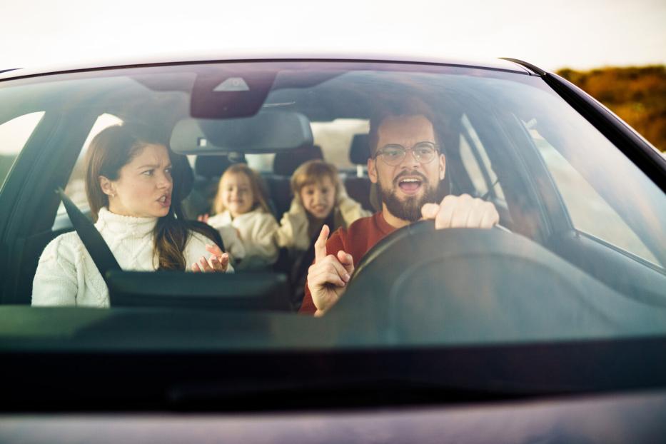 Mother and father are arguing while the children are sitting in the car