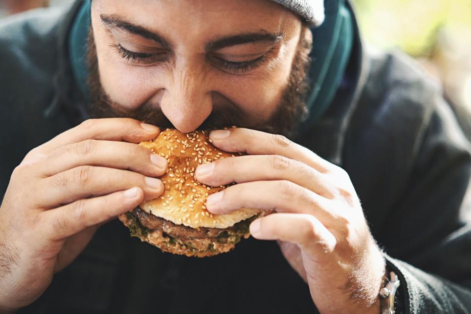 Mann beißt in Burger.