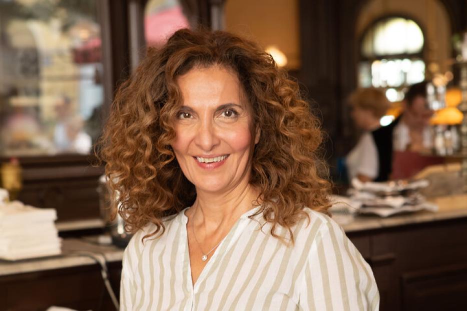 Proschat Madani lächelt in einem Restaurant in die Kamera.