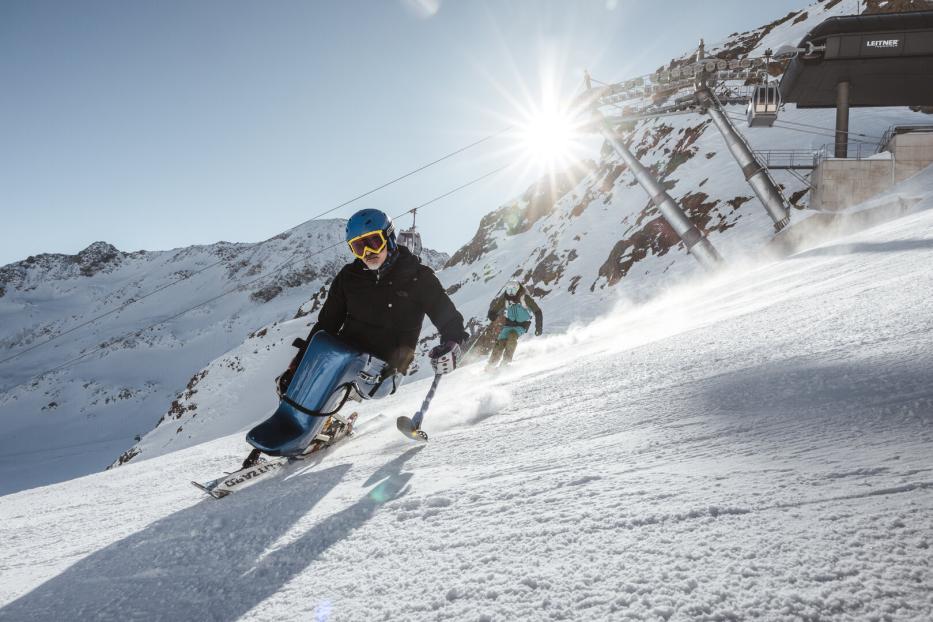 Monoskifahrer fährt eine Piste hinunter