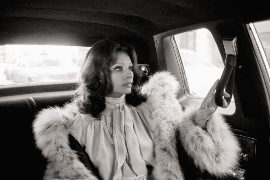 Sophia Loren im Auto, sie hat einen Pelzmantel an und sieht zum Fenster hinaus