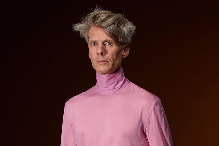 Ein blonder Mann in einem rosa Pulli