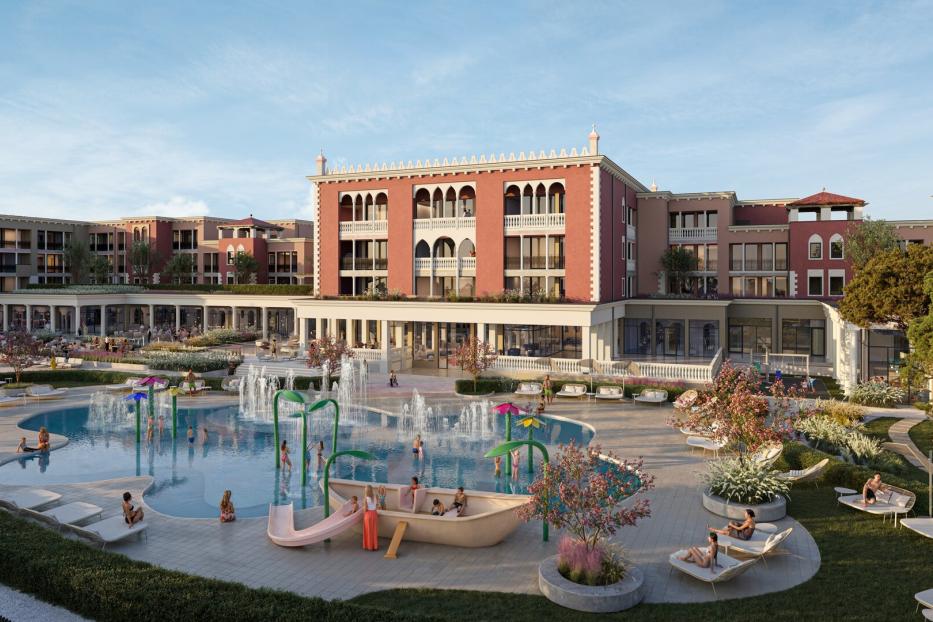 Vor einem großen, venezianisch wirkenden Gebäude entspannen Menschen auf Liegen und spielen Kinder in einem Pool mit Wasserspielen und Rutsche.