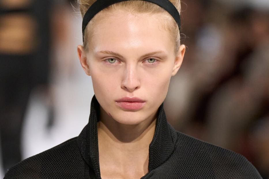 Eine sehr dezent geschminkte Frau im schwarzen Blazer mit schwarzem Haarband