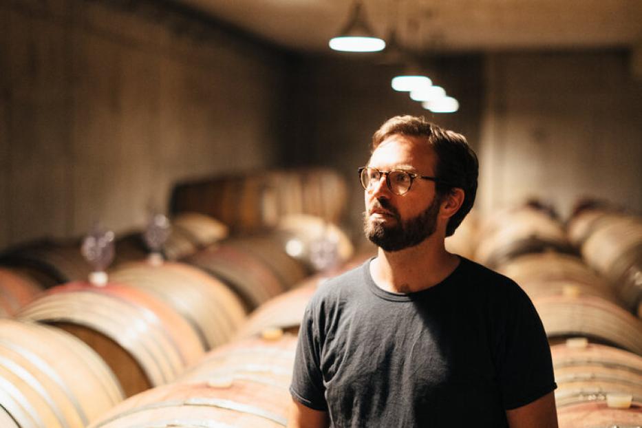 Winzer Franz Weninger steht in seinem Weinkeller zwischen Fässern