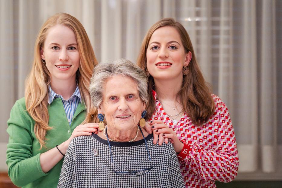Drei Frauen unterschiedlichen Alters posieren lächelnd für ein Porträt.