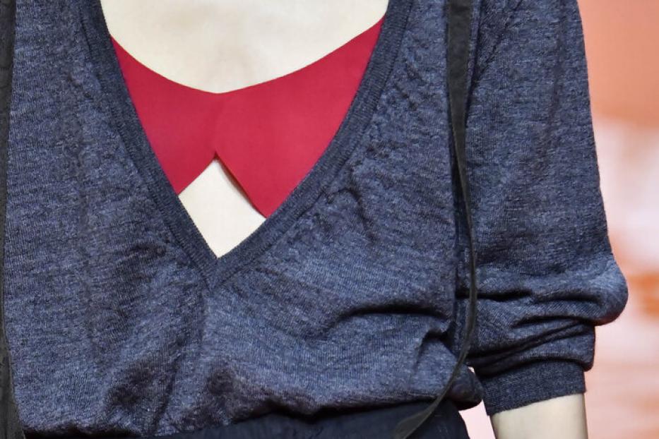 Eine Frau mit einem roten BH, und einer blauen offenen Bluse und einem schwarzen Spitzentuch um die Hüfte