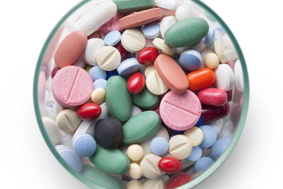 Ein Glas ist gefüllt mit einer Vielzahl von bunten Pillen und Tabletten.