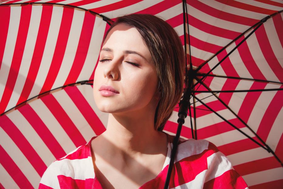 Portrait of a young woman in striped jacket and umbrella.