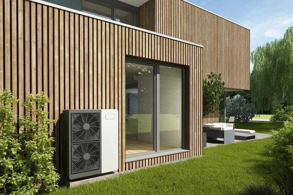 Ein modernes Haus mit Holzfassade, Wärmepumpe und großem Fenster zum Garten.