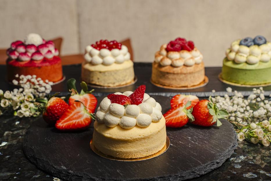 Kleine Törtchen mit Früchten und Creme stehen auf einer dunklen Platte.