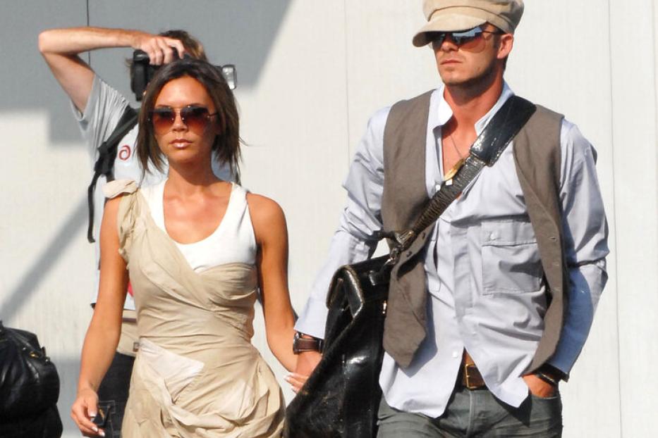  David und Victoria Beckham gehen Hand in Hand an einem sonnigen Tag.. Sie trägt ein Kleid und große Sonnenbrillen, er Stone-Washed-Jeans, Hemd, Gilet, Kappe und große Brille
