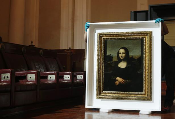 Movers prepare to hang Leonardo da Vinci's "Earlier Mona Lisa" painting ahead of its exhibition in Singapore