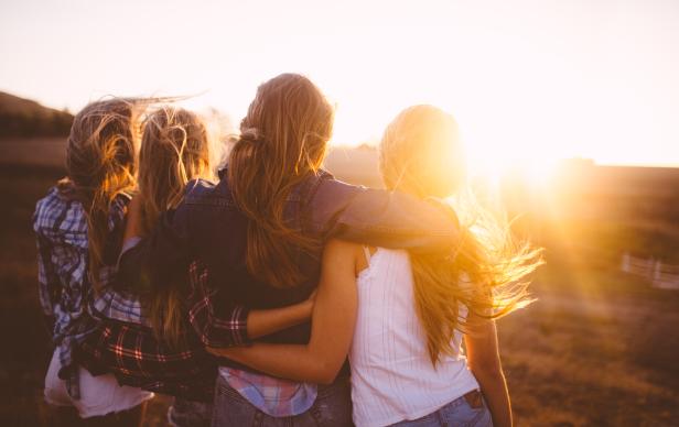 Teen girls facing the sunset with on a summer evening