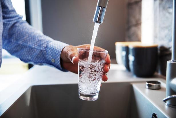 Wasser fließt aus dem Wasserhahn in ein Glas